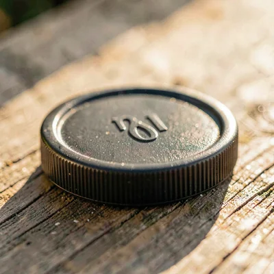 Cropped detail of a lens cap on a beech surface, warm side light