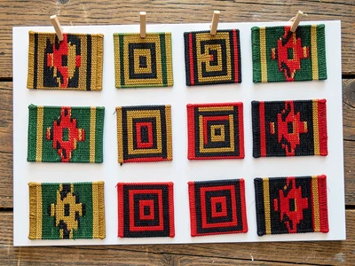 Woven sample card — small kente swatches pinned in rows, flat-lay on wood
