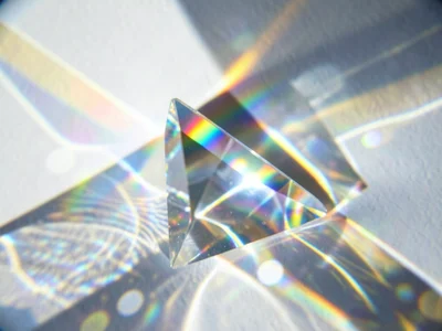 Summer sun through glass bottle creating rainbow projection on white wall
