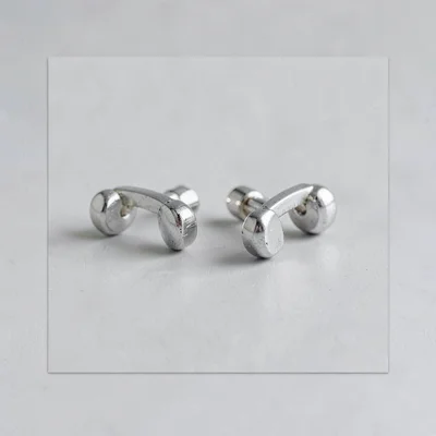 Flat catalog of a pair of silver cuff links on a pale grey square