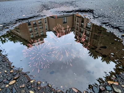 Fireworks reflected in beach tide pool, pyrotechnic burst doubled by still water