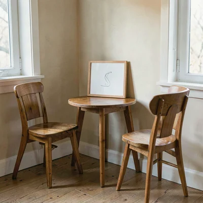 Soft wash of a corner with a single board on a small table, two chairs pulled up