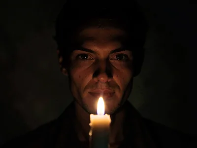 Single candle illuminating face