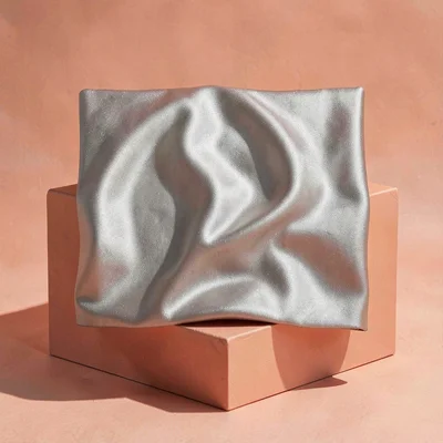 Square ad of a draped silk square against a coral block, hairline cast shadow, e