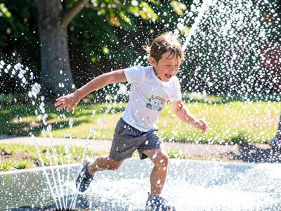 Child running through sprinkler, water and limbs and laughter all streaked toget