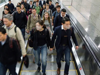 Commuters descending escalator, faces smeared into the collective blur of going 