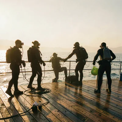 silhouettes of divers gearing up on deck, warm haze