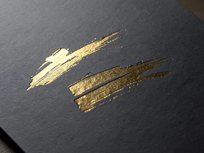 Gold foil stamped abstract brushstroke on charcoal grey paper, metallic flash ca