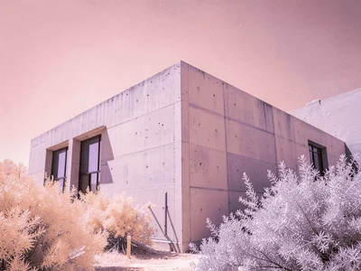 Modernist concrete building with sharp shadows seen against a powdery pink sky a