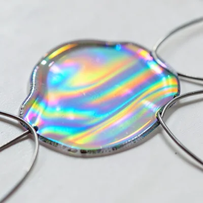 Soap film on a Möbius strip wire frame, continuous surface with flowing iridesce