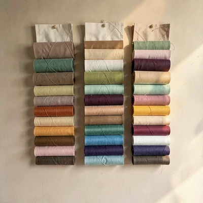 Vertical of a wall hung with rolled needle cases in graduated tones