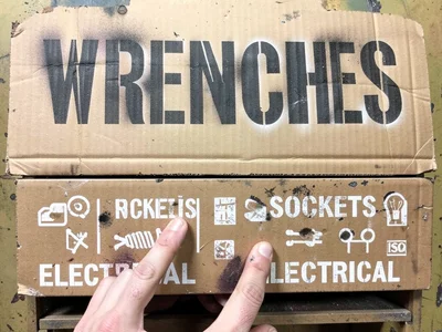 A mechanic's toolbox drawer fronts, each labeled in white stenciled text — WRENC