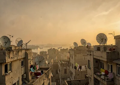 Dusty golden Cairo haze compressing apartment layers, satellite dishes on roofto
