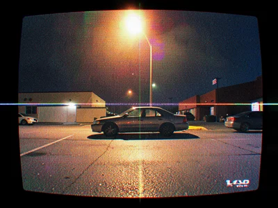 A parking lot with a single car under a flickering streetlight
