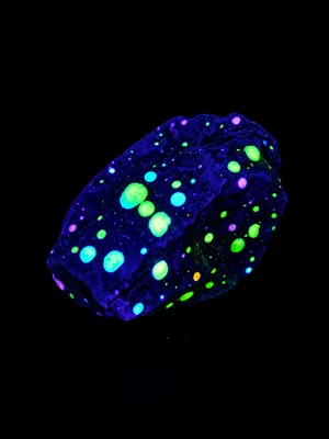 A natural fluorescent mineral specimen — an untreated rock under UV with bright 