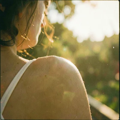 Lover's bare shoulder in morning light, expired SX-70 film creating a yellow fev