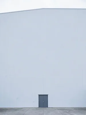 Single door at bottom of towering white warehouse wall