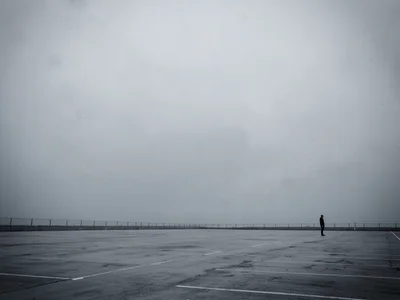 Lone figure at extreme corner of massive empty parking lot
