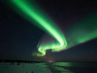 Discrete aurora arc, single sharp green band crossing frame diagonally, clean lu