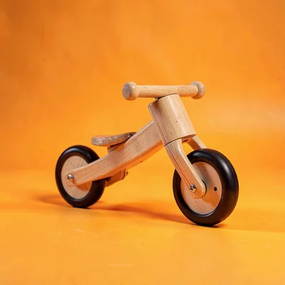 single wooden balance-bike kid-toy at slight tilt on a saturated marigold backdr