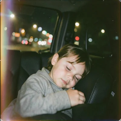 A child sleeping in the back seat of a car at night, streetlights strobing acros