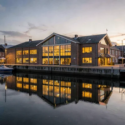 Warm atmospheric of a quayside cultural center facade at dusk with calm harbor w