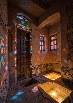 Colored light through qamariya windows in Sana'a, Yemen, carved door frame with 