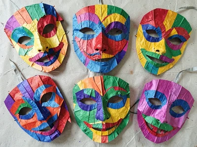A group of papier-mâché carnival masks arranged in a flat-lay overhead view