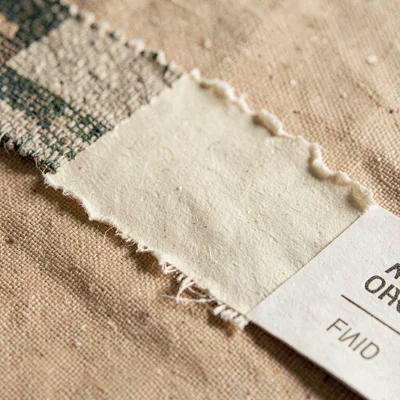 Detail of a torn paper backing on a textile sample card