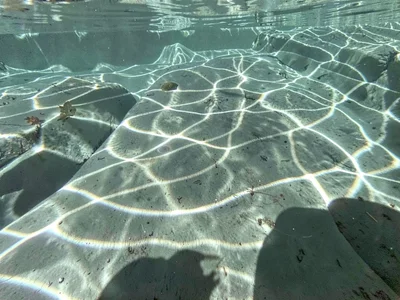 Shadow of surface ripples playing across smooth stone bottom