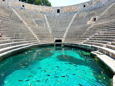 Stone amphitheater partially submerged, seats disappearing into turquoise water,