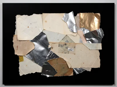 Torn metallic wrapping paper fragments on matte black, reflective scraps catchin
