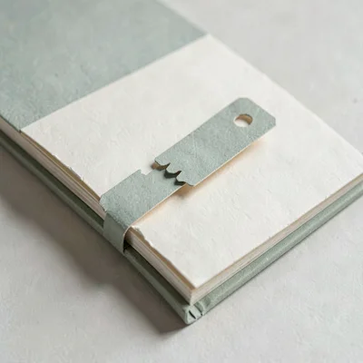 Papercraft onboarding scene of a paper-cut bookmark trailing out of a paper book