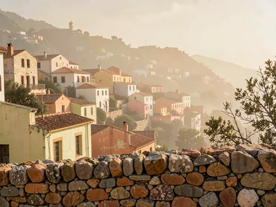 Hazy noon panorama with distant hill town reduced to soft warm masses, foregroun