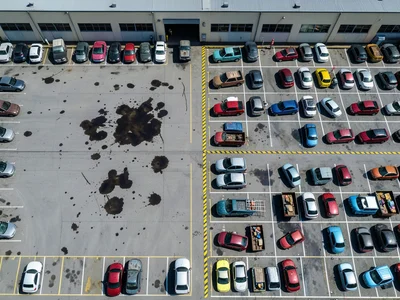 An employee parking lot behind an industrial building at shift change, the lot h