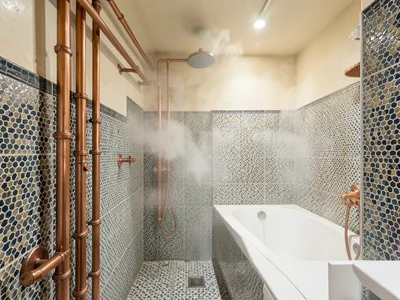 Hammam-inspired bathroom with exposed copper pipes and zellige tile, steam