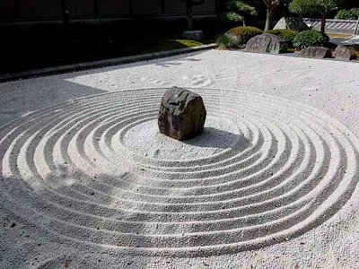 A Zen garden with freshly raked sand, single stone emerging, concentric circles