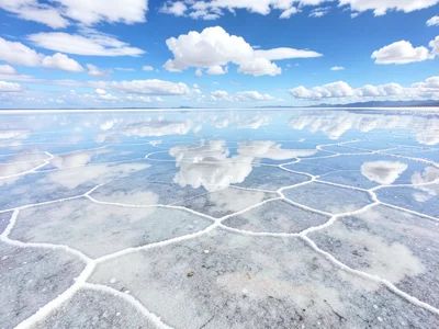 Salt flat at millimeter water depth — perfect reflection of white clouds in a sk