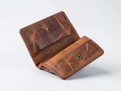 A leather wallet, open to show card slots and bill compartment, warm brown patin