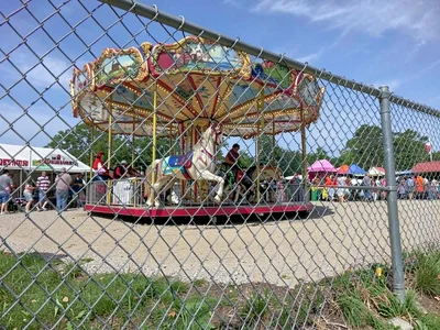 County fair after closing, single carousel horse visible through chain-link fenc