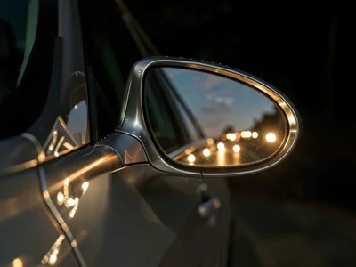 A car's side mirror and door handle lit by nine sources, the metal reflecting an