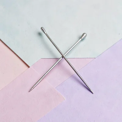Two needle pairs crossed in an X on a flat color block