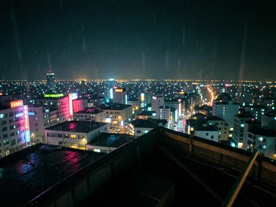 Rooftop view of a dense Asian city at night, sea of lights stretching to horizon