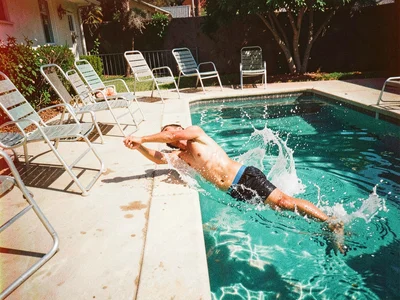 Swimming pool deck, aluminum chairs, someone diving, Kodachrome motion blur spla
