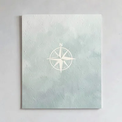 Card with a stylized compass rose in cream and sage, paper grain, no text