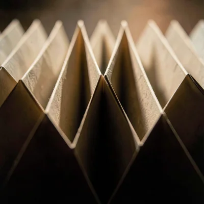 Vertical macro of a paper accordion zigzag receding into shadow