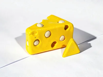 Wide chunky clay slice of swiss cheese in primary yellow with stubby cream-toned