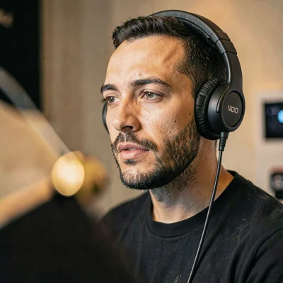 Three-quarter portrait of a VO artist with headphones on, focused expression, po