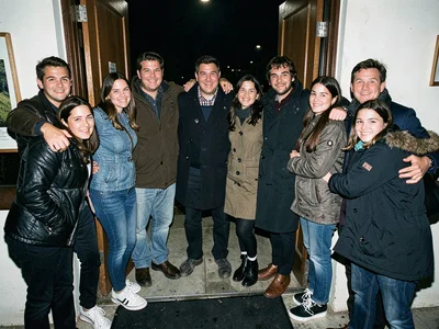 Group photo being taken of departing friends, arms around each other at the door