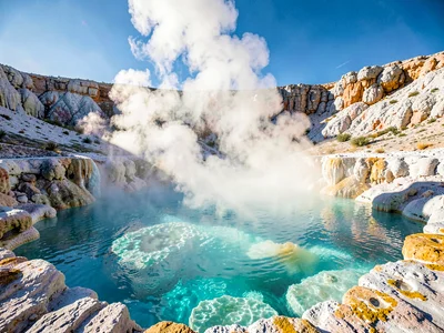 Steam rising from thermal pool catching light